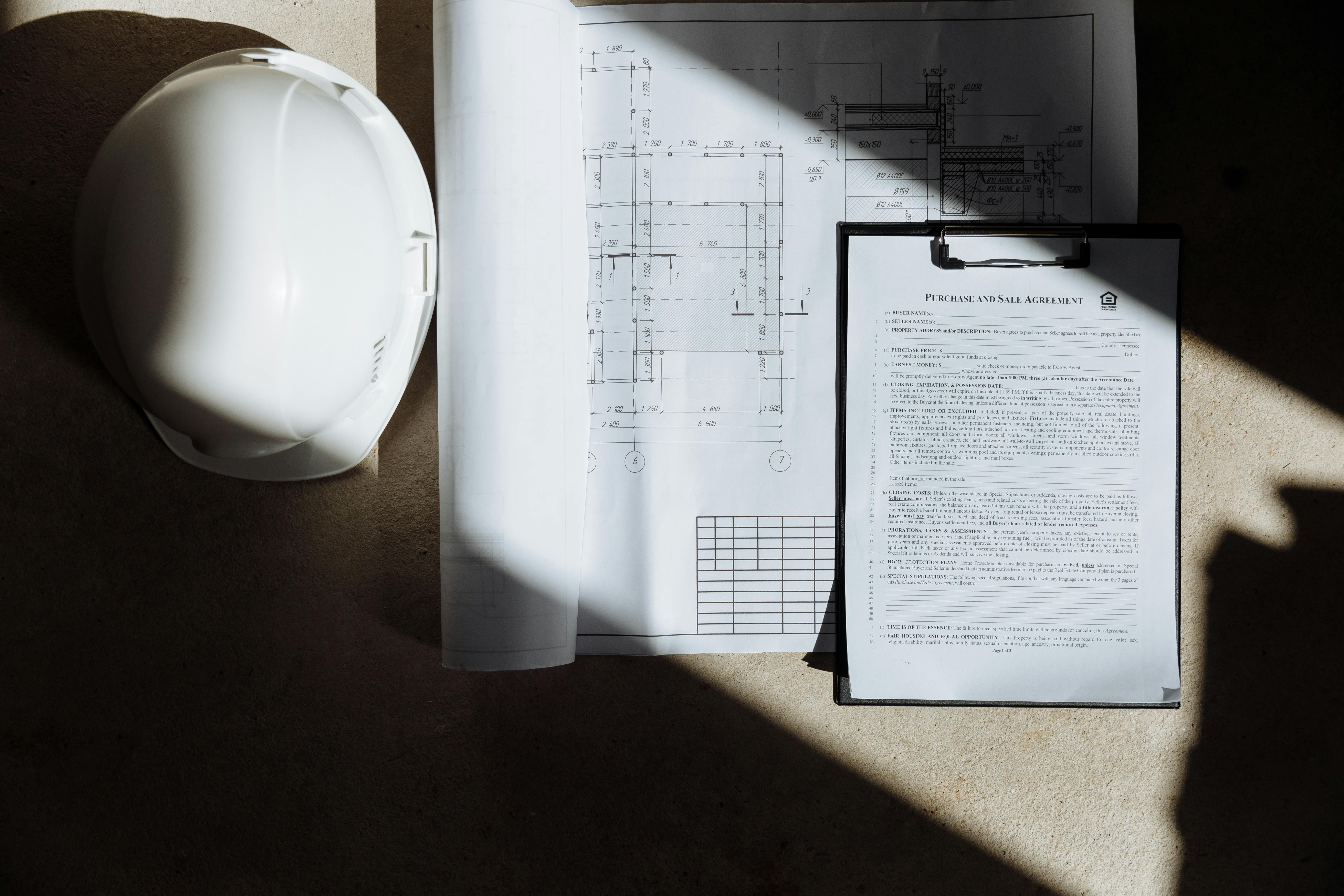 Hard hat, clipboard, and plans illuminated by sunlight
